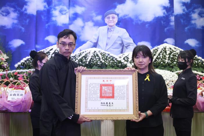 文化部政務次長李靜慧（前右）代表頒贈總統褒揚令，由陳銀輝之子陳柏辰（前左）代表受贈。