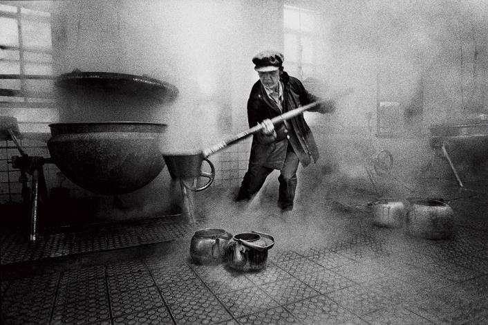 每天至蒸氣瀰漫的公炊廚房燒水、提壺熱水，是過去樂生居民揭開一天序幕的儀式。周慶輝，《行過幽谷》，〈輕度精神病患李亞育是一位熱心的挑水義工〉，1992，國家攝影文化中心典藏。