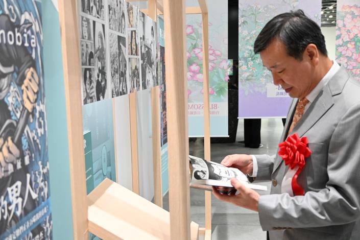 駐日大使李逸洋參觀展覽，拿起漫畫書閱讀