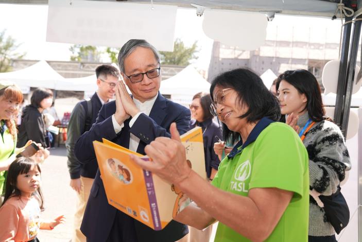 「國家語言生活節」創新書市匯聚多元母語書籍，文化部長李遠（左）於現場從書本學習手語。