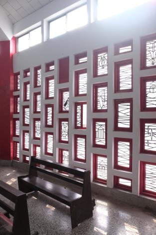 台南果毅天主堂的窗戶設計獨具特色，採用紅白相間的框架，並嵌入鐵藝圖案，透光效果柔和且富有層次感，展現現代教堂建築的美學風格。