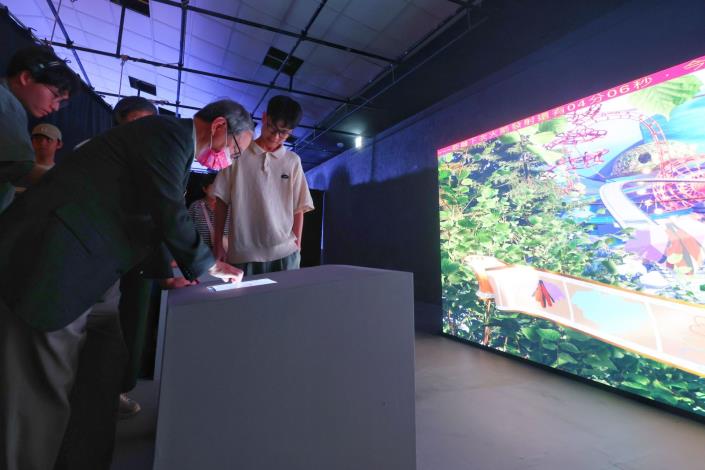 文化部長李遠（左）參觀「互動書展—GoGo_冒險去！」展區，現場體驗互動科技所帶來的沉浸式閱讀體驗。