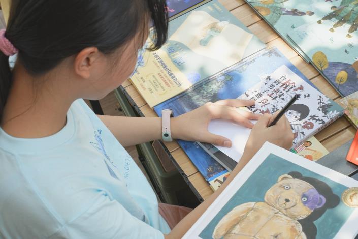 學童閱讀完繪本後，將心得化作文字，仔細寫在明信片上。