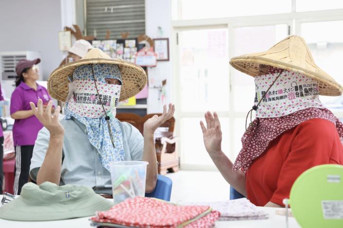 文化部長李遠（左）與《桂花巷》女主角陸小芬（右）體驗龜壁社區婦女「包頭巾」傳統，在社區媽媽協助下，選擇喜歡的花布樣式包住頭，臉也包上特別製作的毛巾布，頭臉包覆緊緊只露出眼睛的造型，還能再加上斗笠，讓大家笑說簡直是「蒙面俠」。