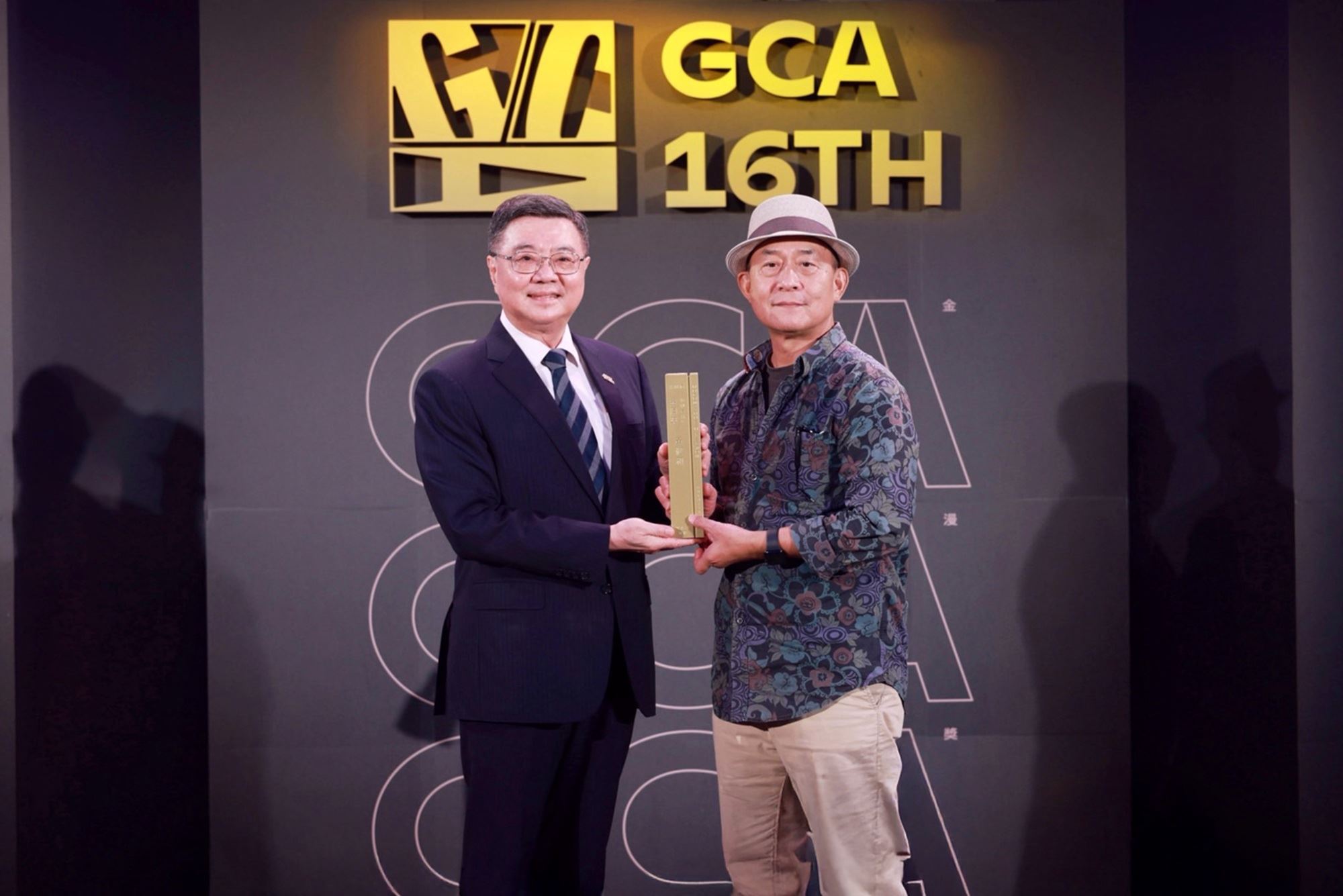 行政院長卓榮泰（左）頒贈第16屆金漫獎「特別貢獻獎」予資深漫畫編輯黃健和。