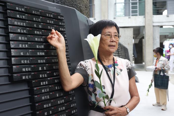 Huang Chun-lan, daughter of political victim Huang Wen-gong, places a flower in front of the monument upon which her father’s name was engraved
