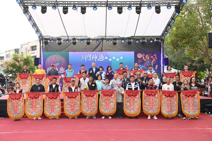 國立傳統藝術中心主任陳悅宜 (後排右6)、嘉義市長黃敏惠(後排右7)致贈紀念旗給參與「2025鬥陣趣 眾將來尬陣」的20組匯演團隊，並邀請活動協辦單位及貴賓一起合影。（國立傳統藝術中心提供）