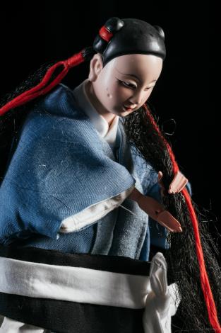 村長女兒靜妹遭村民告密，於散布反詩時被捕，被古閹頭嚴刑拷打。（林育全攝／臺北木偶劇團提供）