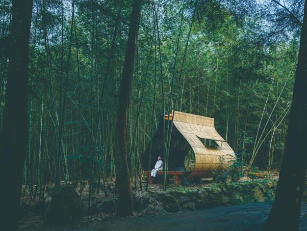 2025《小竹屋計劃：粽子》在南投的孟宗竹林間，范承宗搭建了一座供人歇息的小竹屋，造形靈感來自將竹葉墊在手心裝填餡料的包粽過程。他為行經的人們包一顆來自竹林的粽子，裡頭裝滿了微風、涼蔭、蟬鳴與閒逸。（定影影像攝／范承宗提供）