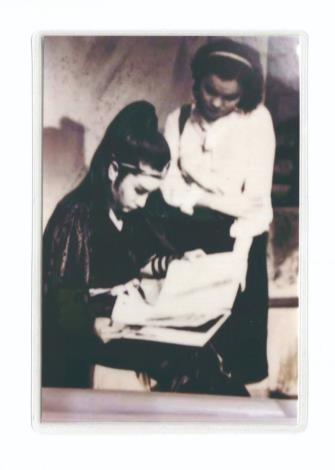 站立者為少女時候的洪鳳秀，楊麗花趁拍戲空檔翻閱她做的剪貼簿。（洪鳳秀提供）