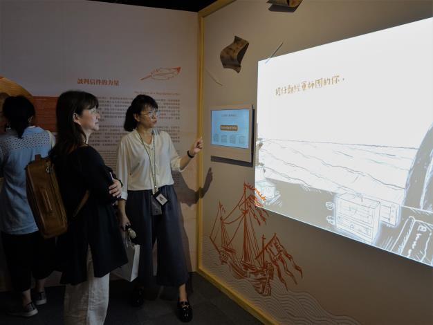 展示組羅聿倫研究助理（右）向文化部政務次長李靜慧（左）介紹互動裝置。