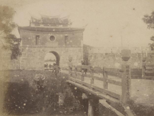 臺北大南門 影像中的南門為閩式城樓建築的樣貌，主體為兩層屋檐的歇山重檐式建築，以紅磚砌成，城門臺座為安山岩石材所建。城門的出入口連接著一座木橋，橋的欄杆上清楚標示著「明治二十九年十月竣成」，為1896年日本領臺第2年時完成的橋樑建築。