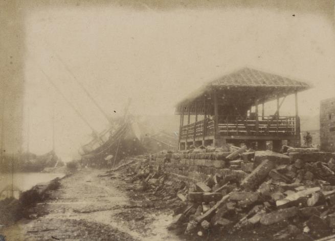 戊戌大水災之大稻埕淡水河岸1898年8月6日，颱風所帶來的豪雨，造成淡水河高漲，當晚暴漲的河水已溢出堤岸，豪雨仍不絕，一直下到7日清晨，造成臺北盆地大淹水，大稻埕受災嚴重。史稱「戊戌大水災」。照片下方標示〈大稻埕淡水河岸〉，影像中可見被大水沖垮的石造堤防，堤防上的木結構屋舍因位置較高而未受損，右後方則有一艘大船被洪水沖上堤岸而擱淺倒於一旁。
