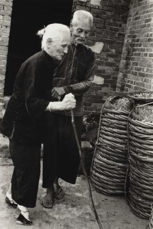 〈恩愛夫妻〉《歲月詩情》系列 攝影家翁庭華作品野柳1962年 在這幅〈恩愛夫妻〉中，我們看到磚房前一對老夫妻相扶持著，這種深情的畫面讓人感受到歲月的洗禮和生活的艱辛。然而，觀者的目光不禁會落在老婦的腳上，那是一雙纏足。