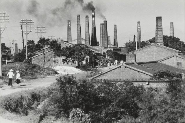 這張作品為黃伯驥於1967年拍攝，紀錄下1920年代至70年代之間，鶯歌一處磚窯廠林立的風景。影像中，鄉村的景致與現代化的工業感衝突並立，以豐富的影像階調與紋理，表現濃煙、磚牆、柴堆與戴斗笠的窯工人們等細節。攝影家定名為〈空氣汙染〉，暗示農業走向工業、現代化社會轉型的困惑。 作品資訊： 黃伯驥〈空氣汙染〉，1967，明膠銀鹽相紙，41.1 × 52.5公分，國家攝影文化中心典藏