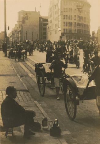 〈街頭賣開水的老婦〉 在熙攘往來的馬路旁，一名老婦人拿個矮凳坐在人行道上，跟前放了一組簡易茶具。在現代化的馬路上，有人力拉車、載客黃包車和自行車，遠處還有一部汽車，沒有明顯的交通規範，車伕在路上各顯神通地穿梭，與後方矗立的現代化建築形成對比。