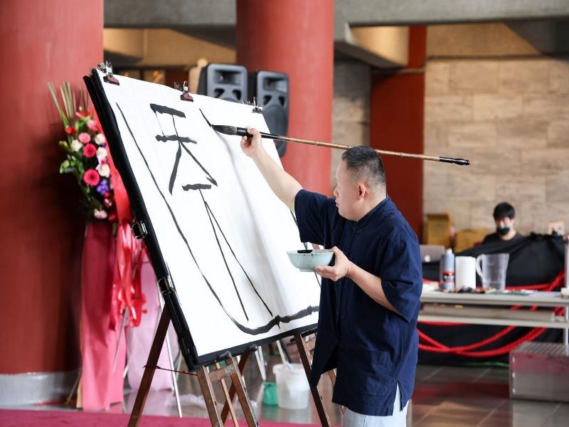 Lin Guang-ting, the young artist with Down Syndrome, wrote calligraphy “The World is for All People” on the scene。