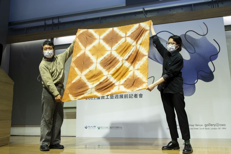參展工藝家廖倫光（左）展示「泥染方巾」成品