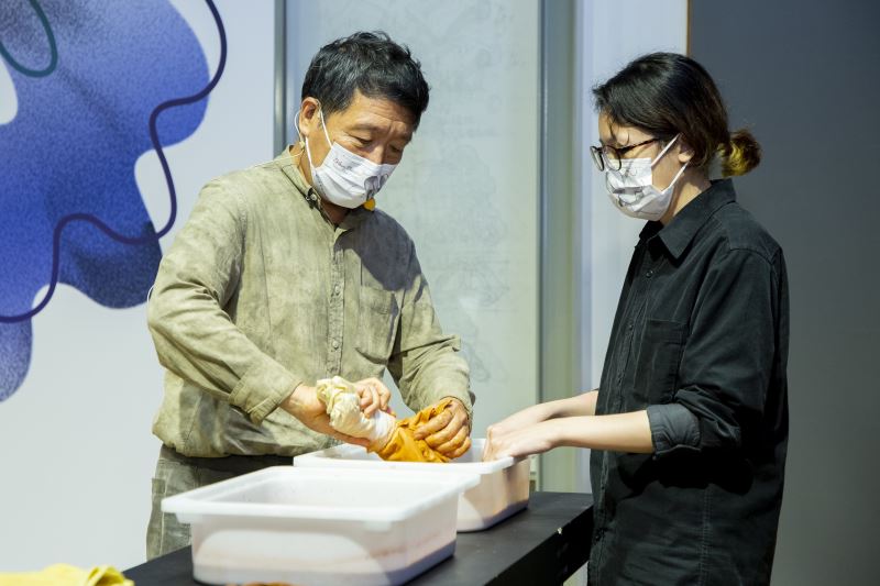 參展工藝家廖倫光（左）示範「泥染方巾」製作過程